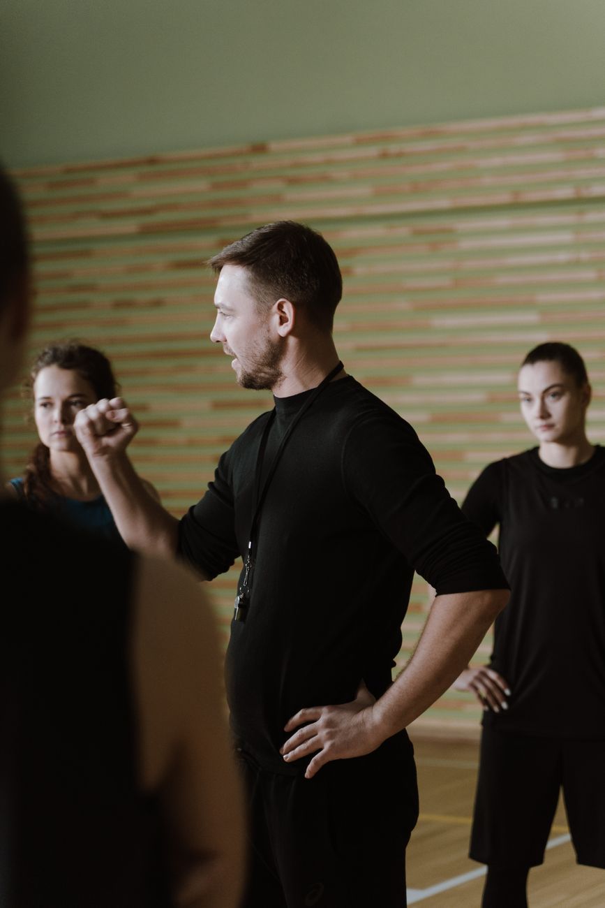a man in black shirt coaching a team of women athletes